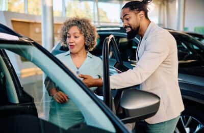 Photo of car salesman showing vehicle to a customer