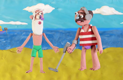 Photo of clay figures on the beach. One with a metal detector and the other shirtless with his hands out to his side