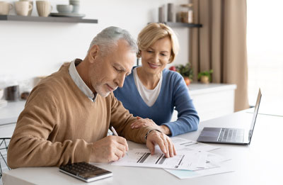Photo of older couple checking their bank statements in front of a laptop