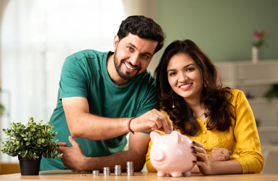 Photo of young couple smiling depositing money into a piggy bank