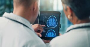 Hands, doctors and tablet for brain scan, neurology and MRI on screen for team collaboration at clinic. People, medical research and healthcare professional with app, xray or neuroscience at hospital
