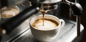 Photo of a modern espresso machine brewing coffee into a ceramic cup. Rich crema forms as coffee pours.